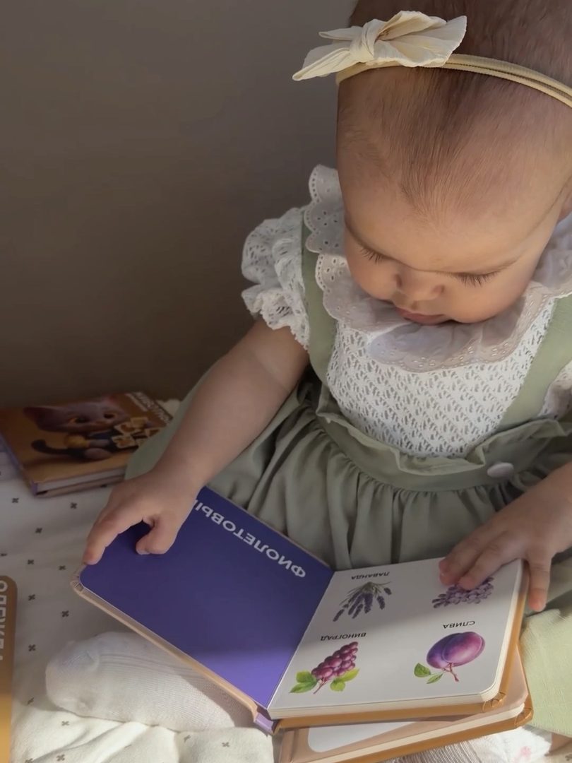 Малышка в платье рассматривает книжку Patricat